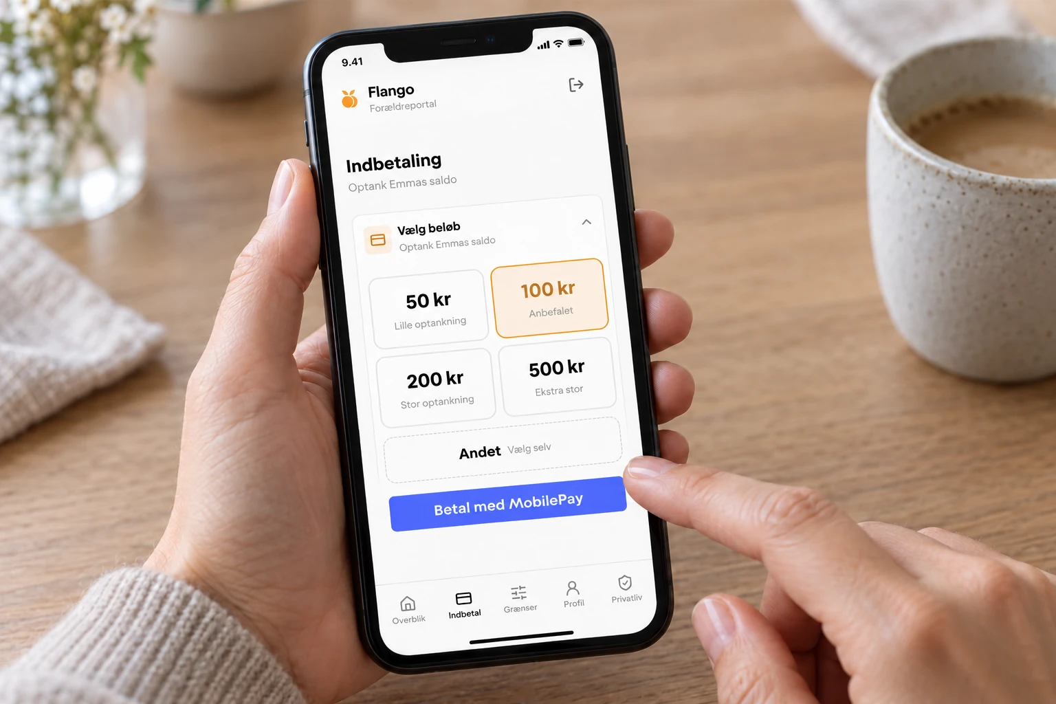 En hånd klar til at indbetale 100 kr med MobilePay i forældreportalen.